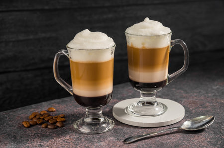 Layered coffee latte drinks. Hot coffee drinks in glass mugs, dark background.