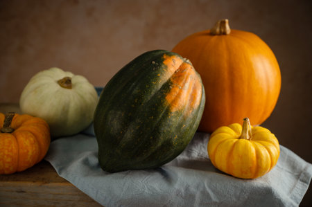 Orange, white and green pumpkins, rustic wooden moody background, autumn concept.