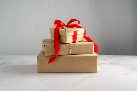 Festive Christmas craft gift boxes with red bows on bright background, Christmas background