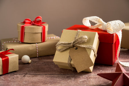 Festive Christmas craft gift boxes with red bows on wooden background. High quality photo