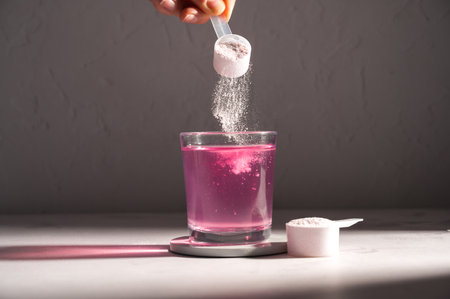 Pouring food supplement powder in glass of water. Collagen, protein powder, vitaminsの写真素材