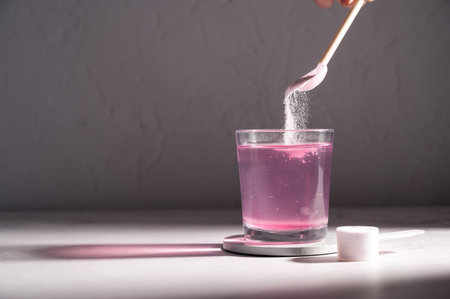 Pouring food supplement powder in glass of water. Collagen, protein powder, vitamins.