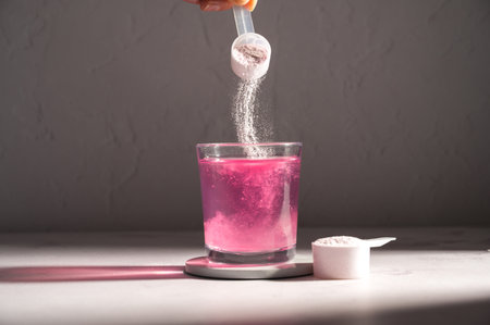 Pouring food supplement powder in glass of water. Collagen, protein powder, vitamins.の写真素材