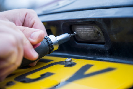 Unscrewing the screw from car light bulb, replacing the old light with a new oneの写真素材