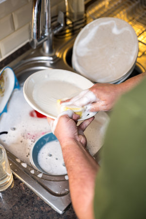 A man washing dishes in the kitchen, home chores, daily routineの写真素材