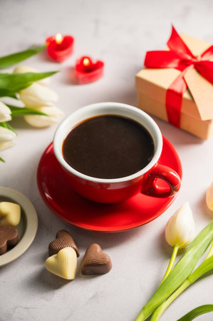 Valentines day. Cup of coffee, heart chocolates, gift box and spring white tulip flower bouquet. Mothers dayの写真素材