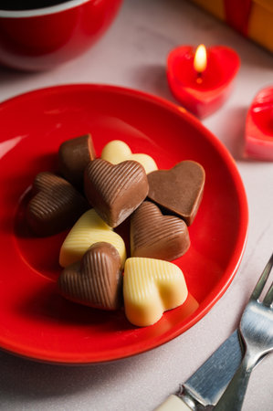 Valentines Day chocolate candies in red plate served with candlesの写真素材