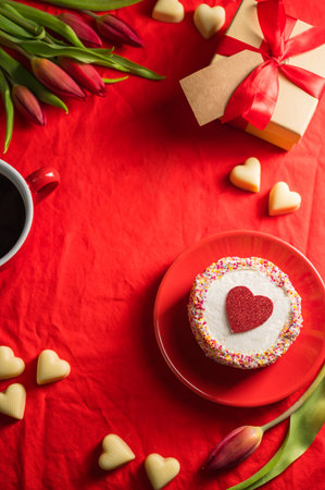 Valentines Day frame background. Cake with red heart, cup of coffee, gift box, heart chocloales and spring red tulip flower bouquet. Top viewの写真素材