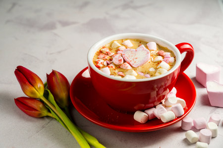Valentine's Day background. Red cup of coffee with heart shaped marshmallows and tulipsの写真素材