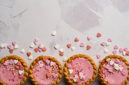 Valentine's day pink background. Pink mini tarts with heart shaped sprinkles. Top view, copy spaceの写真素材