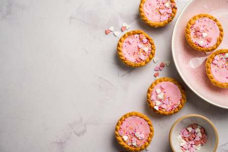 Valentine's day dessert. Pink mini tarts with heart shaped sprinkles. Top viewの写真素材