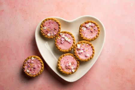 Valentine's day dessert. Pink mini tarts with heart shaped sprinkles. Top viewの写真素材