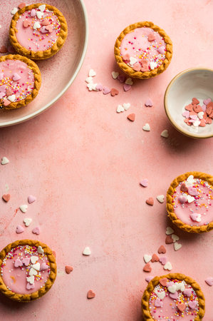 Valentine's day pink background. Pink mini tarts with heart shaped sprinkles. Top view, copy spaceの写真素材