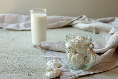 Traditional Beze or Meringues in a glass jar on concrete background. opy space. A glass of milk. Homemade food.の写真素材