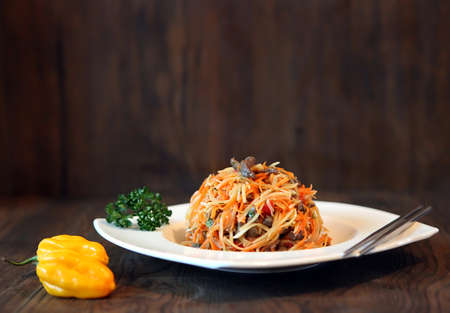 Spicy Korean-style carrot salad with peppers on a dark wooden table. Koryo-saram cuisineの写真素材