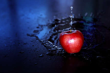 Red glossy Apple with water drops on a black background. Fresh and tasty food concept. Red apple with water droplet on glossy surface on black background. Diet and healthy lifestyle foodの写真素材