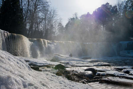 Winter snow landscapes, frozen waterfall and icicles view. Cold wintertime at the river. Stunning frozen waterfall icicles on winter day. Winter cascade.の写真素材