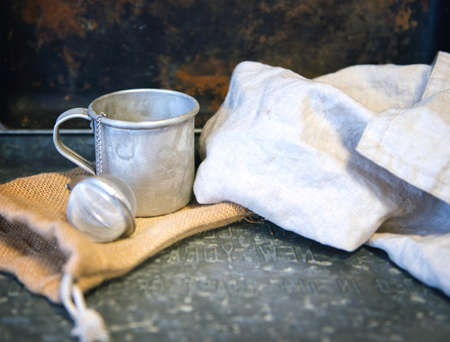 Metal mug or stainless teacup with tea egg behind the cotton white towel. Creative rustic vintage style. Nostalgy conceptの写真素材