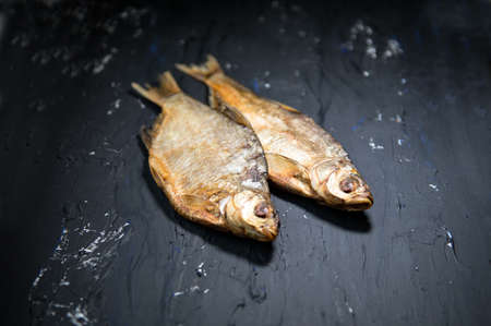 Salted dried river fish Makerel on a black background. Dry salted fish, top view, copy space....