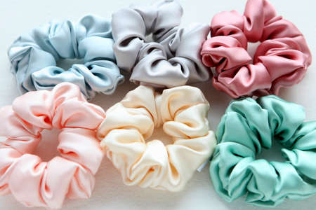Lot of Colorful silk Scrunchies isolated on white. Flat lay Hairdressing tools and accessories. Hair...