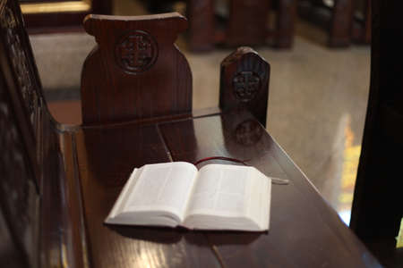 Open Holy Bible on a old wooden church bench.