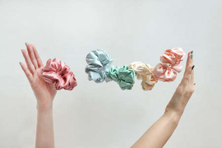 Lot of floating Colorful silk Scrunchies on womas hands isolated white. Hairdressing tools and accessories. Hair Scrunchies, Elastic HairBands, flying or falling Scrunchie Hairband for girl. copy spaceの写真素材