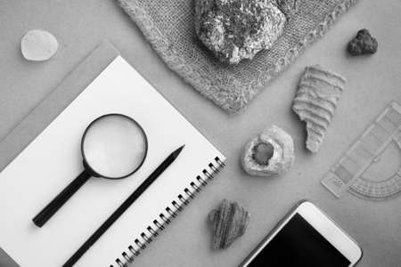 Stone samples, loop, notebook and mobile phone at geological laboratory on wooden tableの写真素材