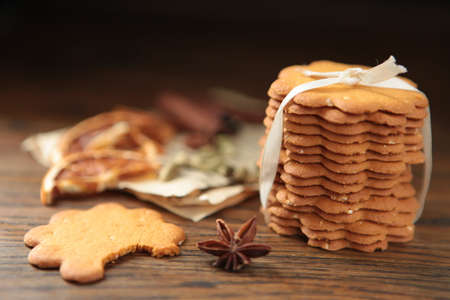 Homemade tasty gingerbread cookies on dark rustic wooden table, copy space. Healthy vegan organic nutrition concept. whole grain cookies with dried oranges, cinnamon stick, old paper, spices and herbs. dark photoの写真素材