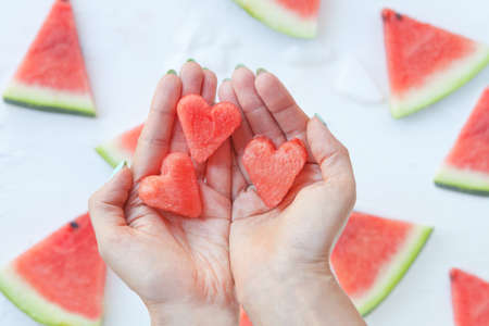 Watermelonhearts slices on womans hands. Sliced watermelon on white background. Flat lay, top view. Love and care concept.の写真素材