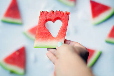 Watermelonhearts slices on womans hands. Sliced watermelon on white background. Flat lay, top view. Love and care concept.の写真素材