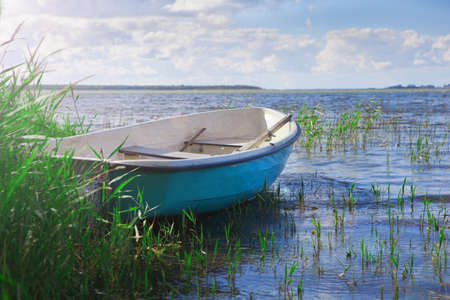 blue fishing boat on the sea near the seaweed grass at summer time. Sunny weather. Old fishing boat and flare light.の写真素材