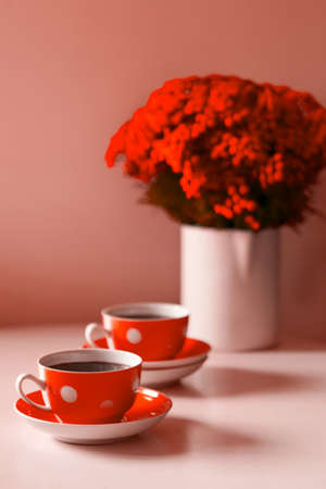 Two red coffee cups on white background, coffee break and caffeine addiction concept. red flowers on...