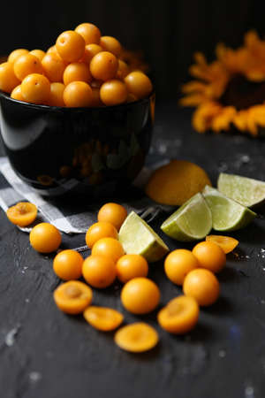 Yellow plums with lemon and lime on the black background. Ingredients for a jam-tasty plums. Food photography. Vertical image. Yellow sunflower, Autumn Concept,の写真素材
