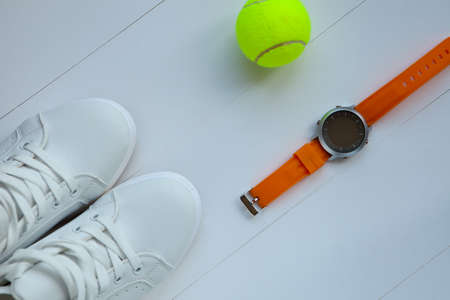 white tennis shoes, tennis ball and orange sport watch. sportequipment. sportswear. Participation in competition.の写真素材