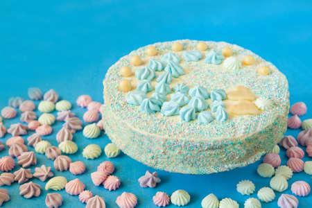 blue cake with candies for babyshower party with meringue. Homemade cake for a newborn boy On a blue background.の写真素材