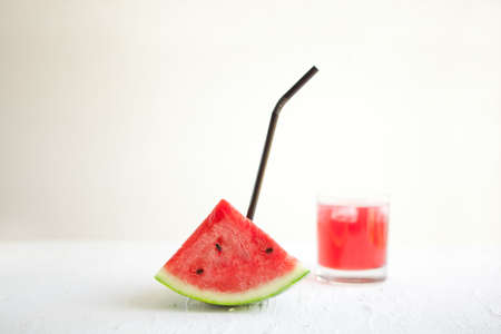 watermelon slice with straw and juice on the white board. Delicious drink - vegetarian cocktail from fresh fruit with ice. conceptual imageの写真素材
