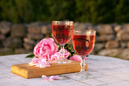 two glasses with rose wine and pink peony bouquet. delicious refreshing drink, huge blossoming flowers at the tableの写真素材