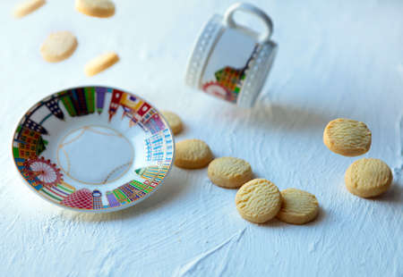 flying biscuits, plate and cup of tea. Falling cookies with mug. Food levitation on white background