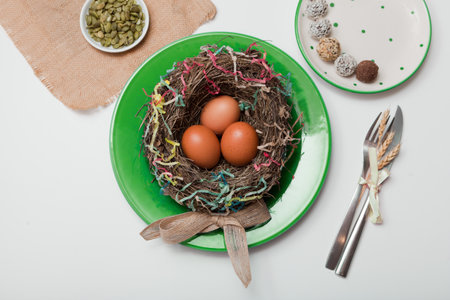 nest with eggs on green plate. Happy Easter. Stylish white table, flat lay. Natural eggs spring