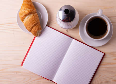 a white ceramic cup with black espresso, french croissant as breakfast or snack concept on rustic, natural texture wooden surfaceの写真素材