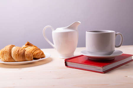 a white ceramic cup with black espresso, french croissant as breakfast or snack concept on rustic, natural texture wooden surfaceの写真素材