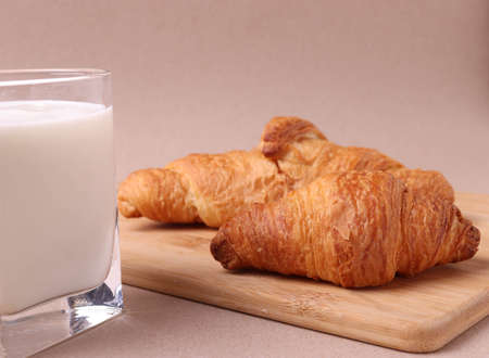 french baked pastry croissants and a glass of milk on rustic beige backgroundの写真素材