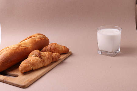 french baked pastry croissants and a glass of milk on rustic beige backgroundの写真素材