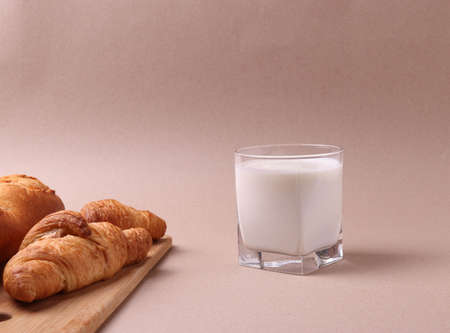 french baked pastry croissants and a glass of milk on rustic beige backgroundの写真素材