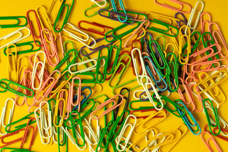 staples paper clips of different colours on the yellow background