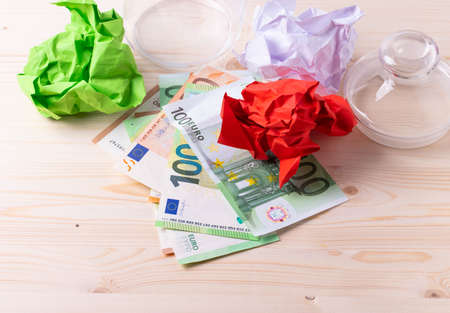 european paper banknotes of hundread euros in a glass jar on the white wooden desk as a concept of finance, currency rates or savingsの写真素材