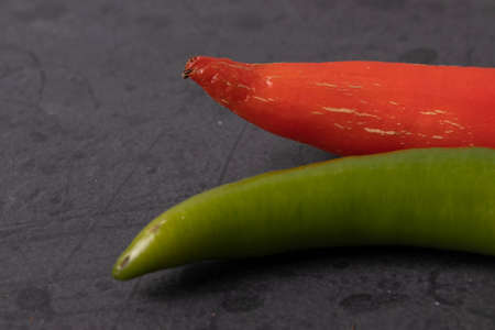Red and green spicy chilly papers on the dark stone concrete surface