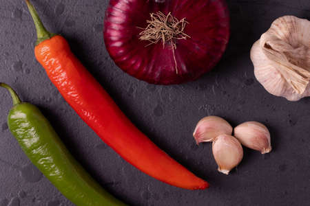 Red and green spicy chilly papers on the dark stone concrete surfaceの写真素材