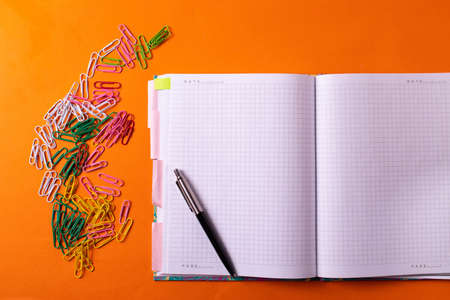 different stationary supplies items on orange office or studying deskの写真素材