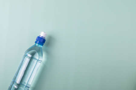 a plastic bottle of water on mint blue surface